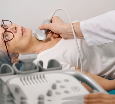 Uzist diagnostician conducts examination of the thyroid gland on ultrasound machine for an elderly lady, the doctor uses modern equipment